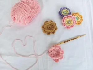 Crochet flowers with pink yarn and a gold crochet hook